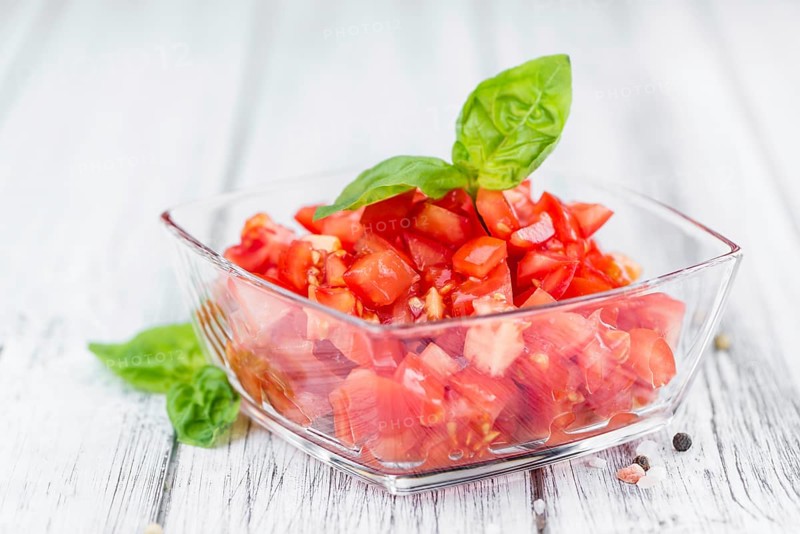 Tomatoes (diced) as high detailed close-up shot on a vintage wooden table (selective focus)