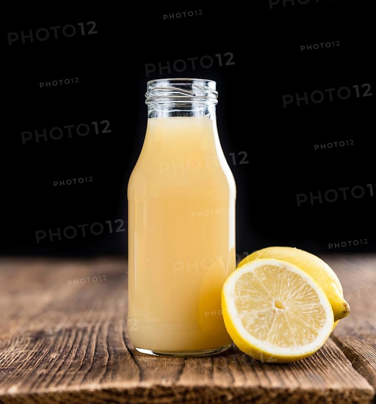 Homemade Lemon Juice on an wooden table (selective focus) as detailed close-up shot