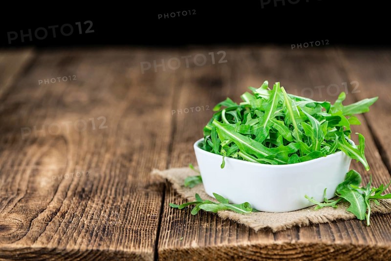 Fresh Arugula (selective focus) as detailed close-up shot on vintage background