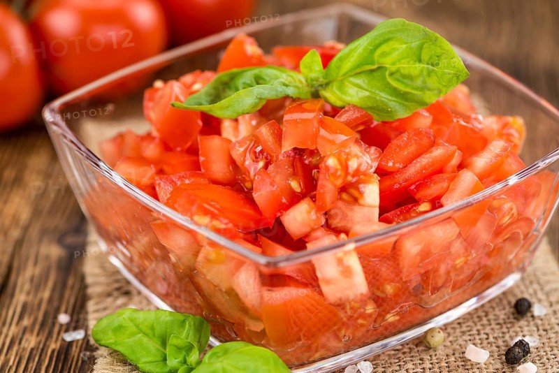 Tomatoes (diced) as high detailed close-up shot on a vintage wooden table (selective focus)