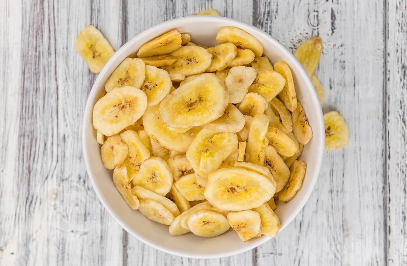Homemade Dried Banana Chips on an wooden table as detailed close-up shot, selective focus