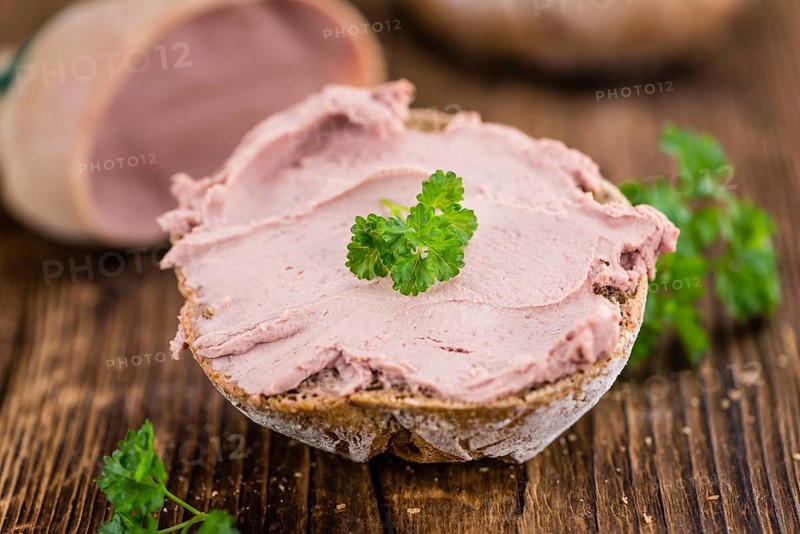 Roll with Liverwurst (German cuisine) on an old wooden table as detailed close-up shot (selective focus)
