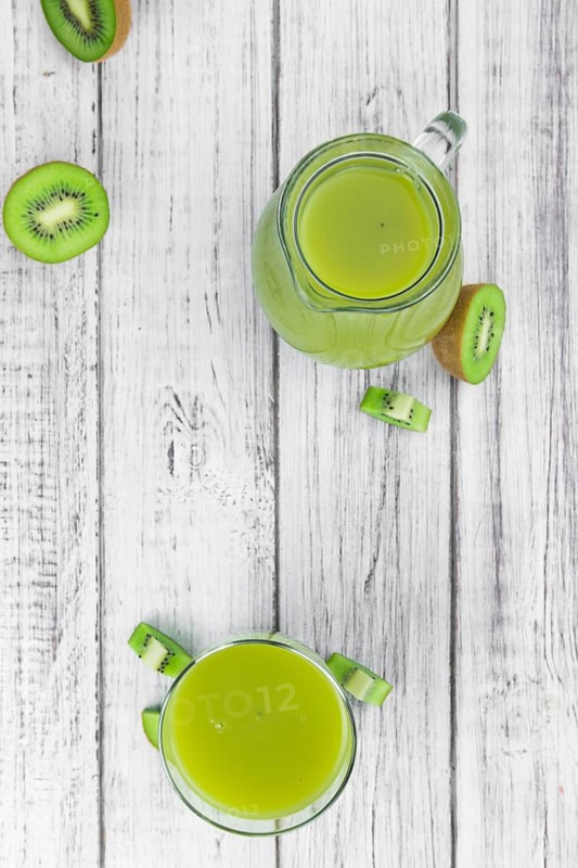 Wooden table with fresh made Kiwi Smoothie (close-up shot, selective focus)