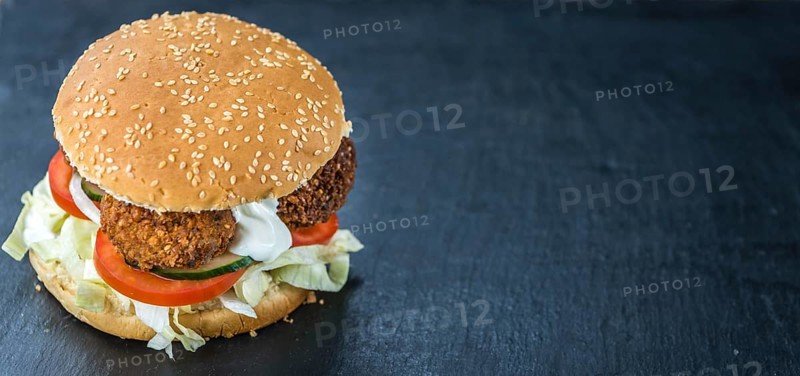 Homemade Falafel Burger on a dark slate slab (close-up shot, selective focus)