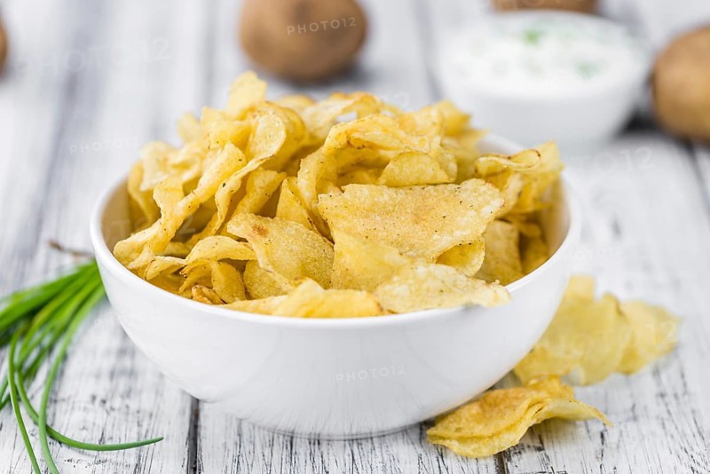 Potato Chips with Sour Cream taste as high detailed close-up shot on a vintage wooden table (selective focus)