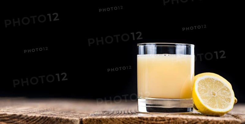 Fresh made Juice (lemon) on an old and rustic wooden table (selective focus, close-up shot)