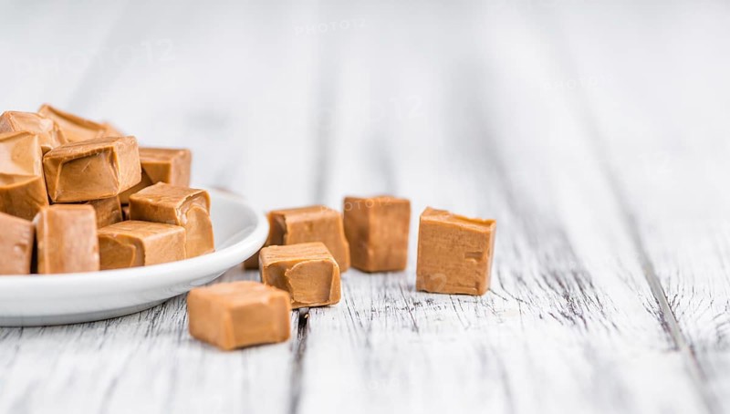Caramel pieces as high detailed close-up shot on a vintage wooden table (selective focus)