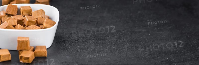 Portion of Caramel candy as detailed close up shot on a slate slab (selective focus)