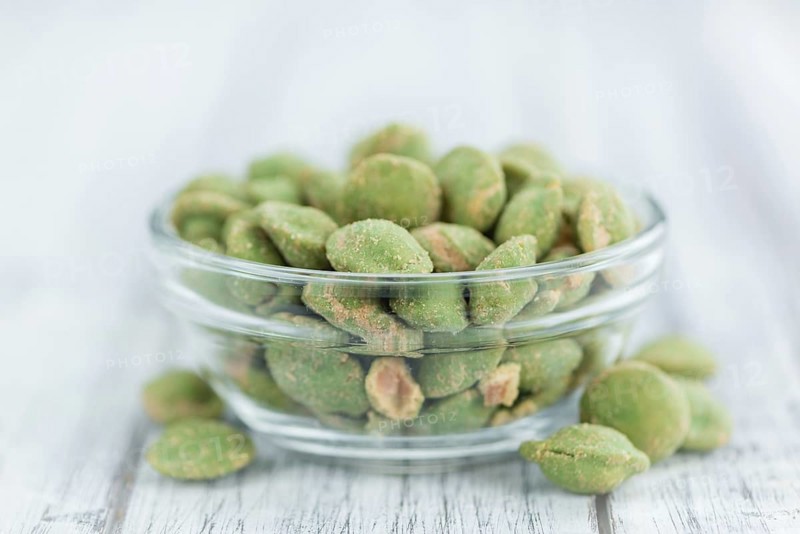 Peanuts (with Wasabi flavor) on an old wooden table as detailed close-up shot (selective focus)