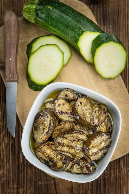 Fresh made Zucchinis (grilled) on an old and rustic wooden table (selective focus, close-up shot)