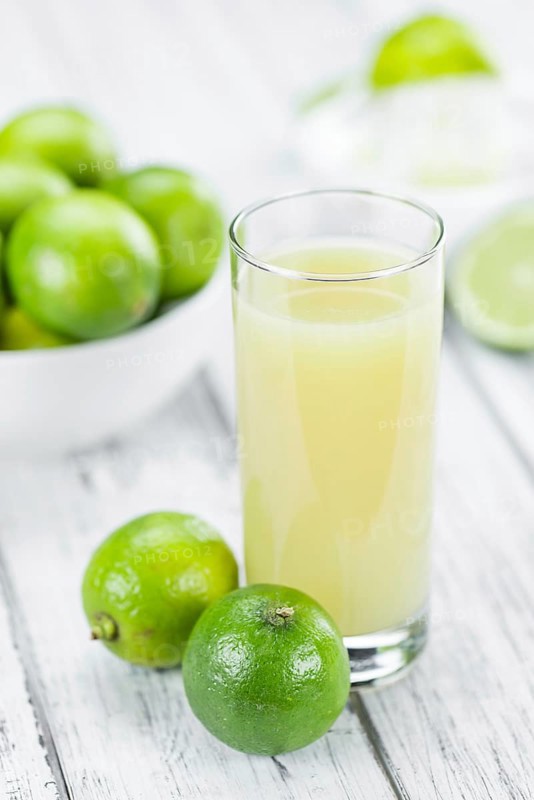 Fresh Lime Juice as high detailed close-up shot on a vintage wooden table (selective focus)