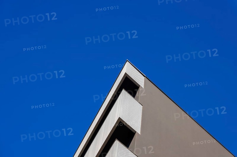 Beautiful Modern Concrete Design Building with Metal Balcony Against Blue Clear Sky in Switzerland