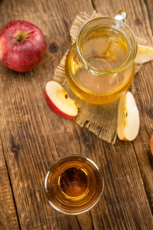 Apple Cider as high detailed close-up shot on a vintage wooden table (selective focus)