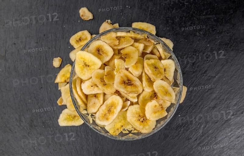 Portion of Dried Banana Chips on a rustic slate slab, selective focus, close-up shot