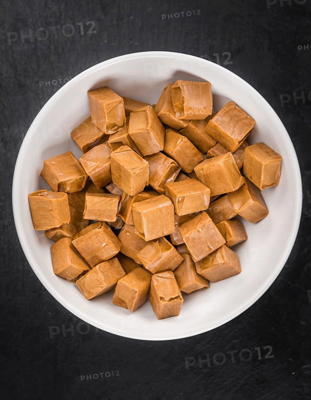 Portion of Caramel candy as detailed close up shot on a slate slab (selective focus)