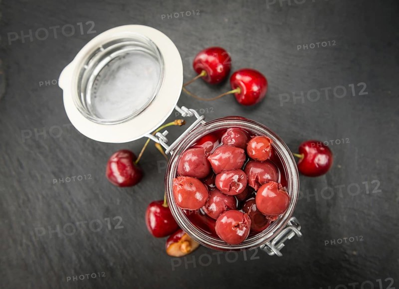 Portion of Preserved Cherries as detailed close up shot on a slate slab, selective focus
