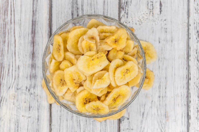 Homemade Dried Banana Chips on an wooden table as detailed close-up shot, selective focus
