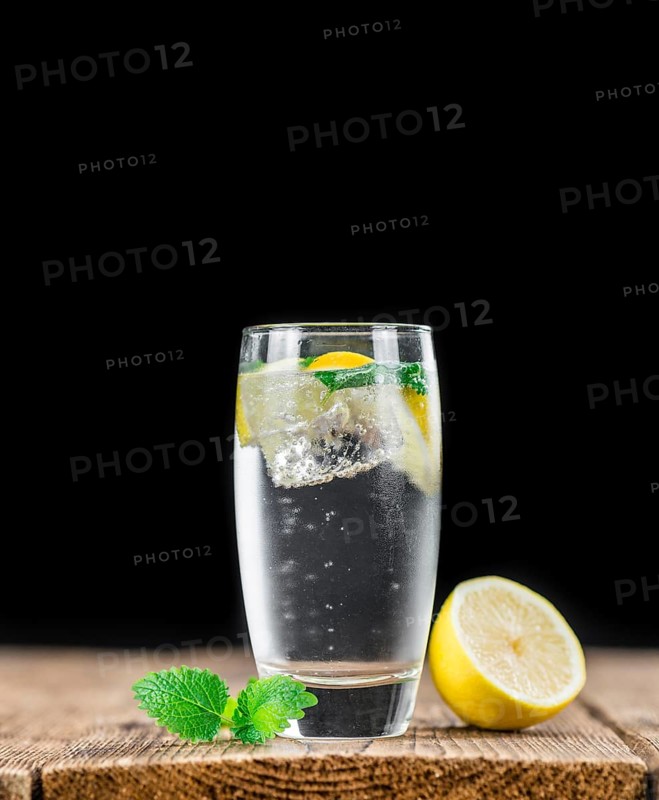 Lemonade (with Balm) as high detailed close-up shot on a vintage wooden table (selective focus)