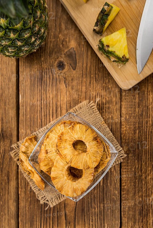 Pineapple rings (dried) on an old wooden table as detailed close-up shot, selective focus