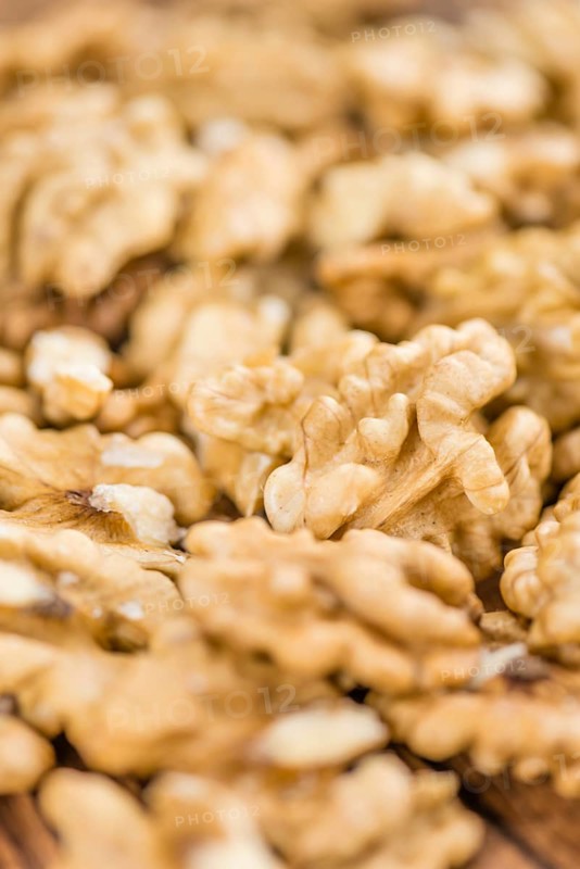 Walnuts (kernels) on an old wooden table as detailed close-up shot (selective focus)