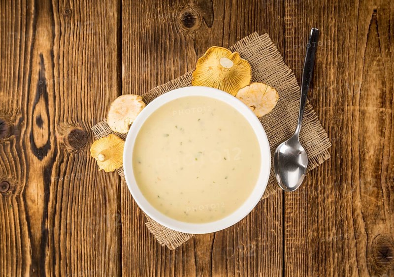 Chanterelle Soup as high detailed close-up shot on a vintage wooden table, selective focus