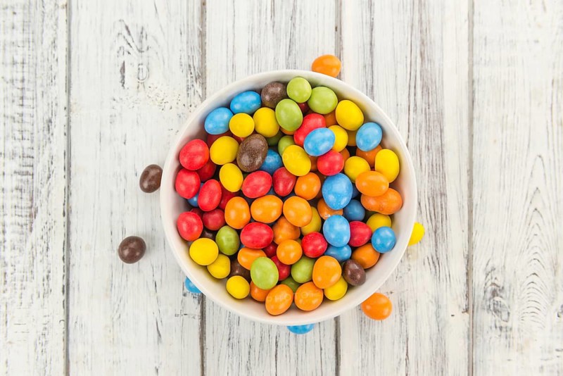 Cocolate coated Peanuts on rustic wooden background (close-up shot)