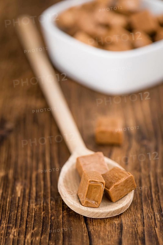 Portion of homemade Caramel on wooden background (selective focus, close-up shot)
