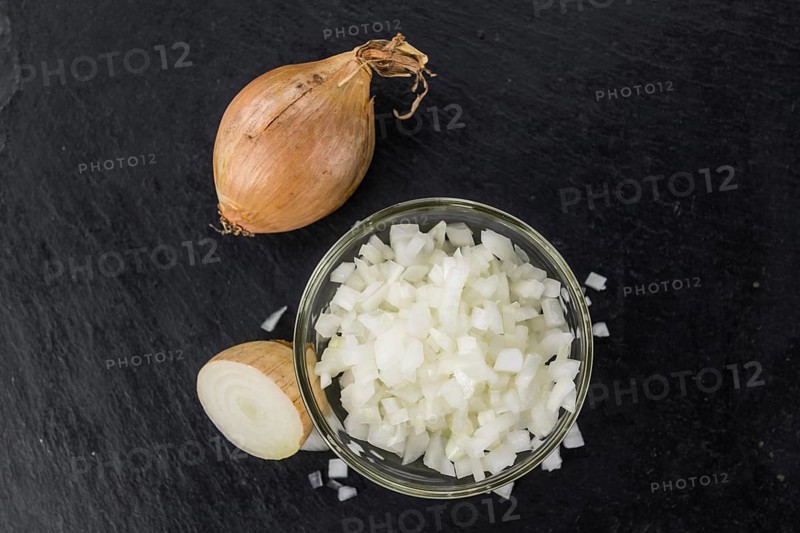 Some White Onions (dices) on a slate slab as detailed close-up shot, selective focus