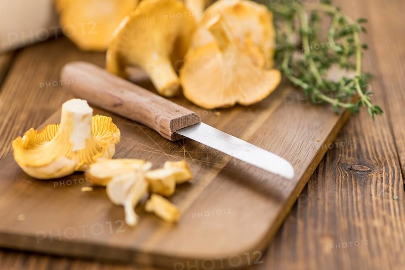 Portion of fresh harvested Chanterelles on wooden background as detailed close-up shot (selective focus)