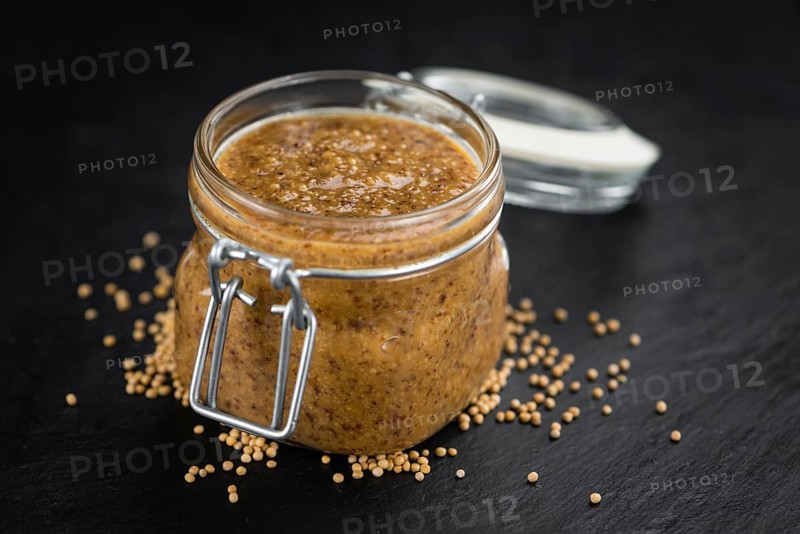 Portion of Mustard (sweet) as detailed close up shot on a slate slab (selective focus)