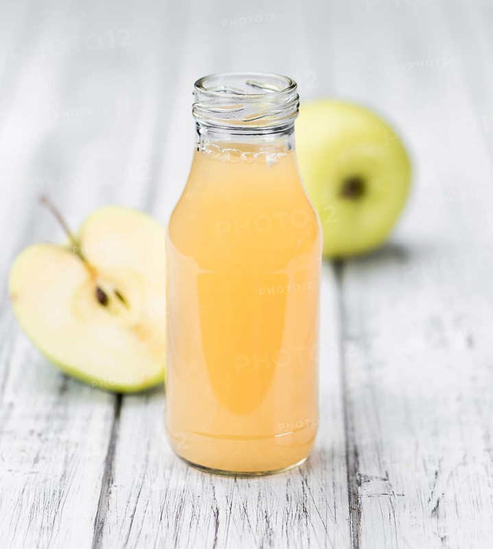 Apple Juice on an old wooden table as detailed close-up shot (selective focus)