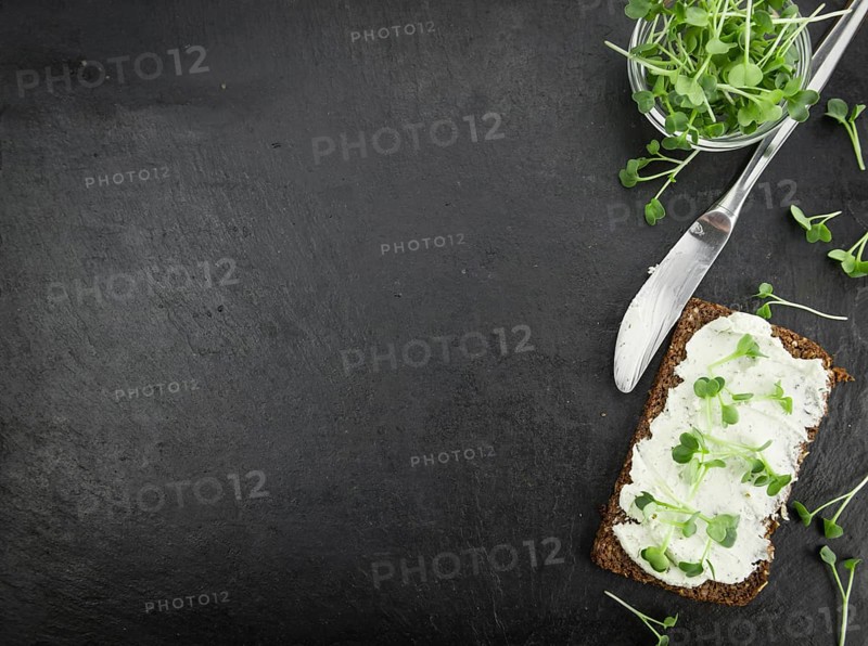 Fresh cutted Cress with creamy Cheese on a slice of bread (selective focus, close-up shot)