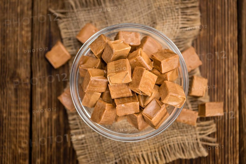 Caramel pieces as high detailed close-up shot on a vintage wooden table (selective focus)