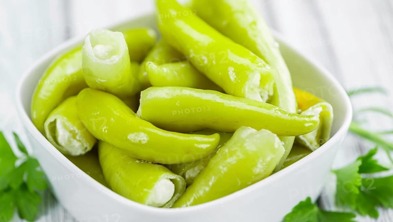 Fresh made Green Chilis (filled with cheese) on an old and rustic wooden table (selective focus, close-up shot)