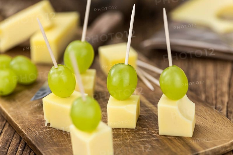 Vintage wooden table with Cheese blocks and grapes as detailed close-up shot (partyfood)