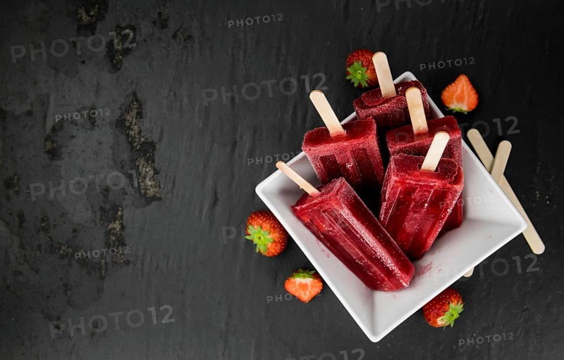 Slate slab with homemade Strawberry Popsicles (selective focus, close-up shot)