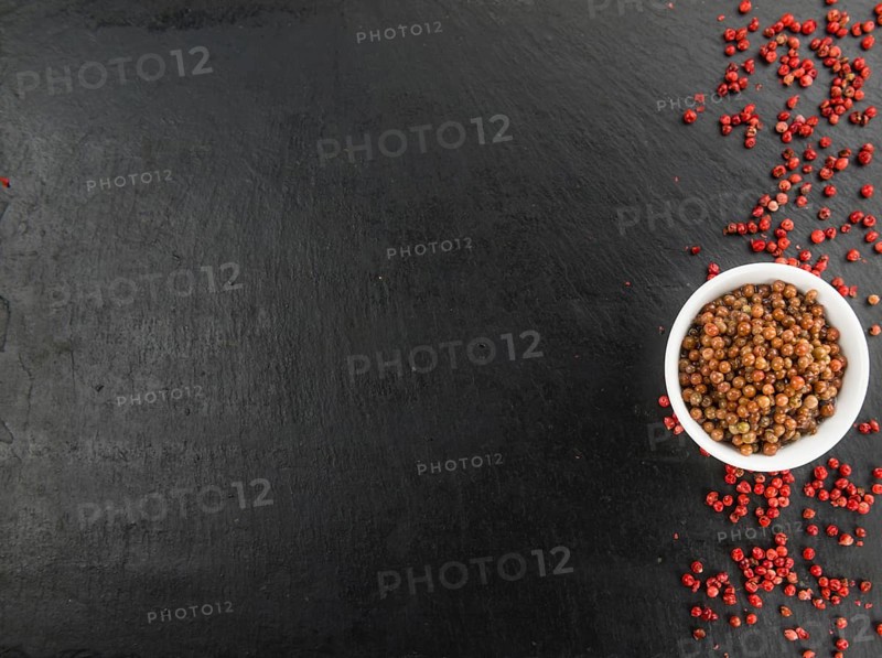 Some Pink Peppercorns (preserved) on a slate slab as detailed close-up shot, selective focus