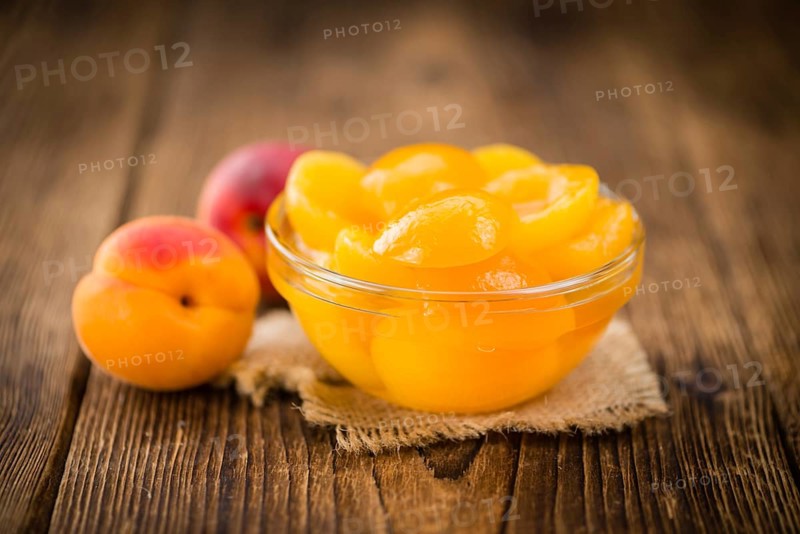 Canned Apricots on an old wooden table as detailed close-up shot (selective focus)