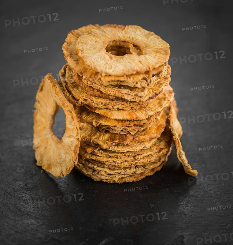 Portion of Dried Pineapple Rings on a rustic slate slab, selective focus, close-up shot