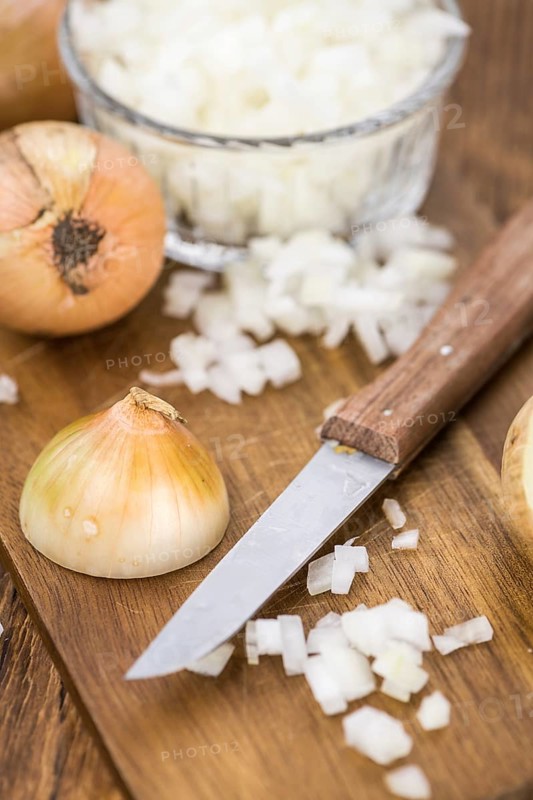 Chopped white onions on an old wooden table as detailed close-up shot, selective focus