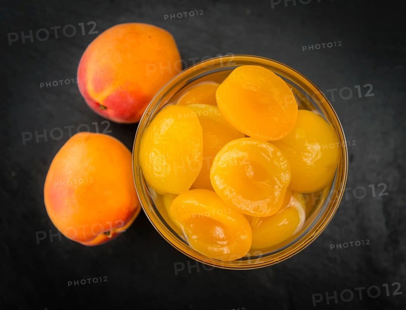 Portion of Canned Apricots as detailed close up shot on a slate slab (selective focus)