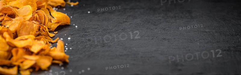 Some Sweet Potato Chips on a slate slab as detailed close-up shot, selective focus