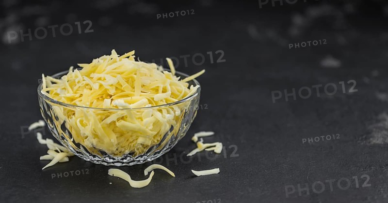 Homemade Grated Cheese (close-up shot) on a vintage slate slab