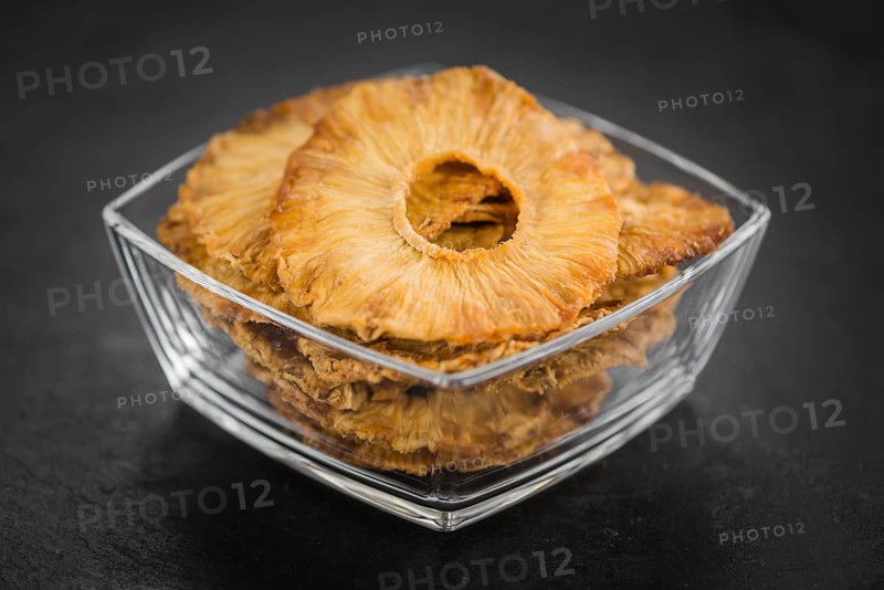 Portion of Dried Pineapple Rings on a rustic slate slab, selective focus, close-up shot