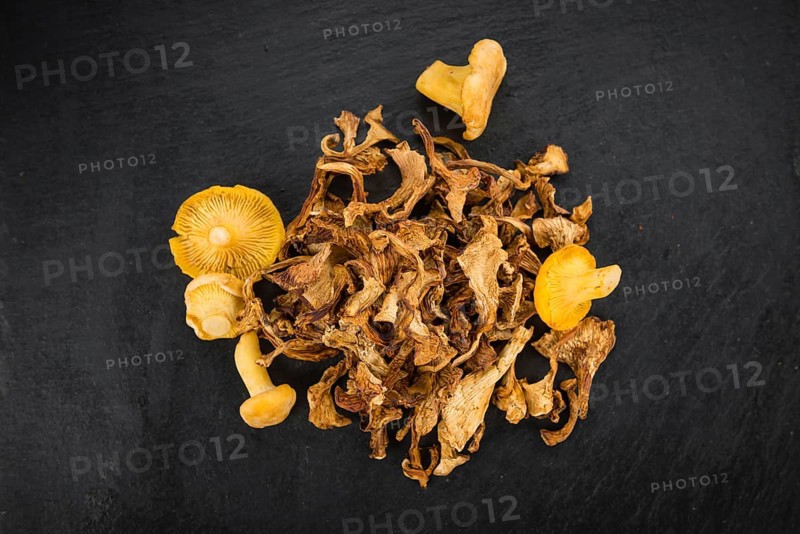 Portion of Dried Chanterelles as detailed close up shot on a slate slab, selective focus