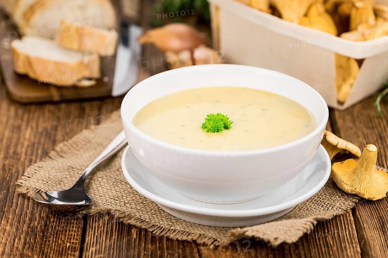 Creamy Chanterelle Soup on an old wooden table as detailed close-up shot, selective focus