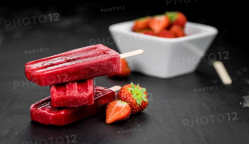 Slate slab with homemade Strawberry Popsicles (selective focus, close-up shot)