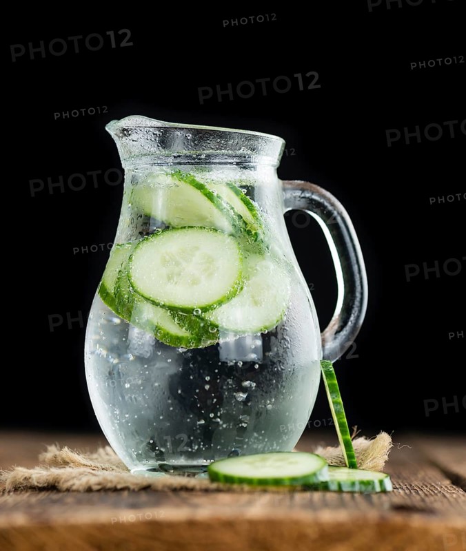 Fresh made Cucumber Water as high detailed close-up shot on a vintage wooden table, selective focus
