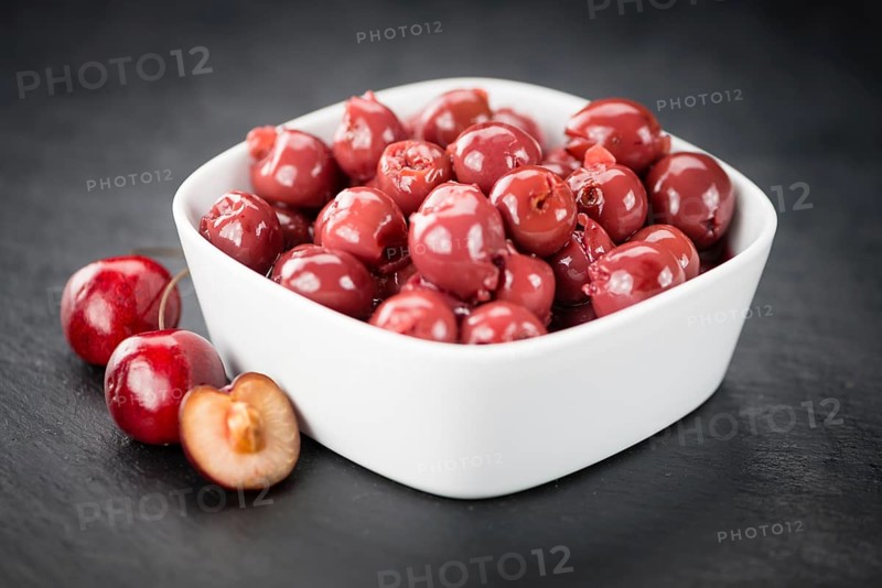 Portion of Preserved Cherries as detailed close up shot on a slate slab, selective focus
