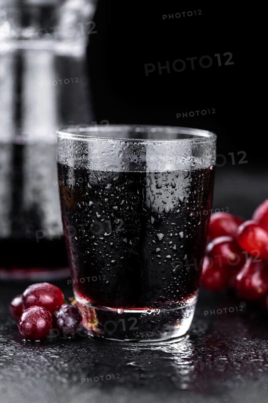 Portion of healthy Red Grape Juice on a slate slab (selective focus)